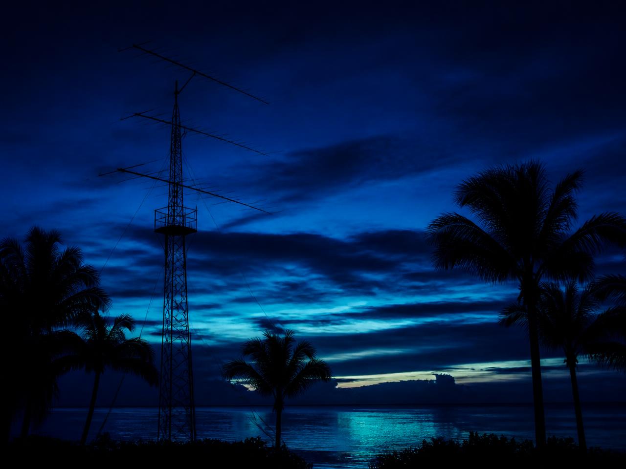 Antenna tower and palm silhouettes against a Marco Island dusk sky